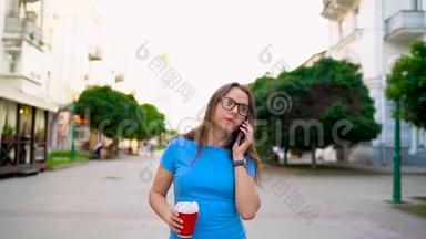 女人在智能手机<strong>上说</strong>话，喝着咖啡走在街<strong>上</strong>。 慢动作